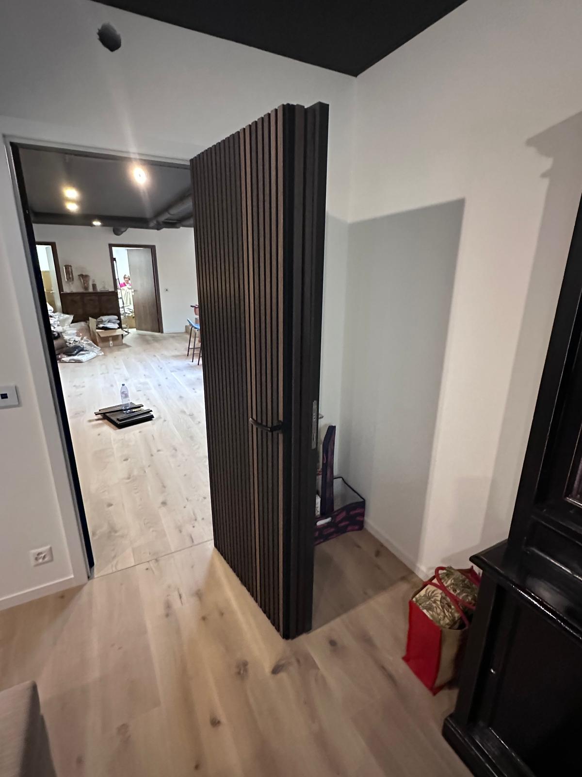 Porte invisible ouverte dans l'habillage tasseaux
